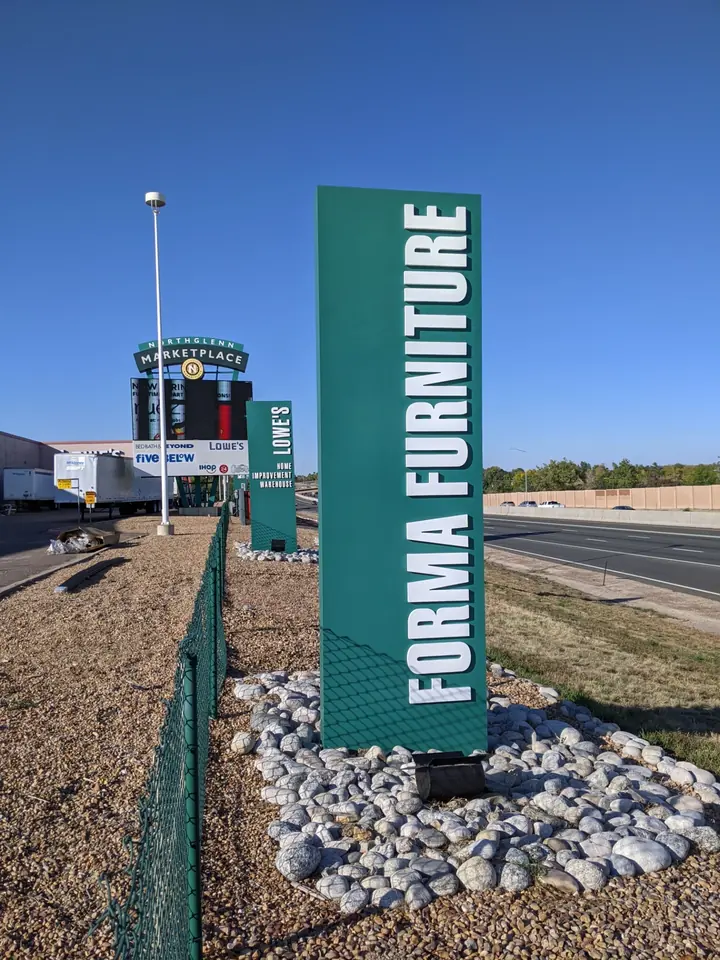 Forma Furniture vertical monument sign with dimensional white letters on a green panel