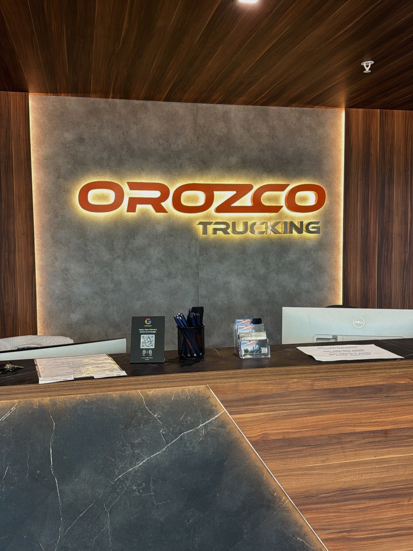 Illuminated Orozco Trucking dimensional logo sign on an office reception wall