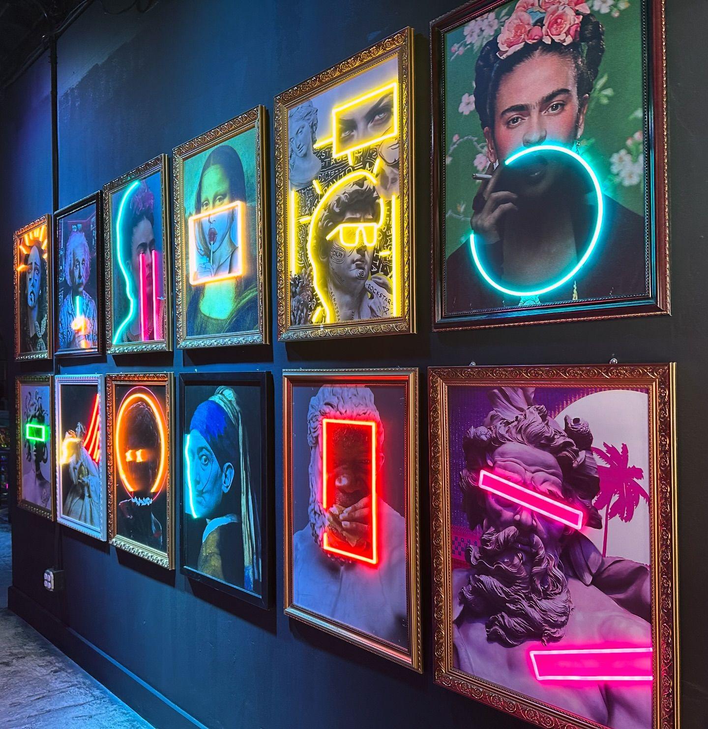 Nine illuminated framed artworks installed together on a dark feature wall